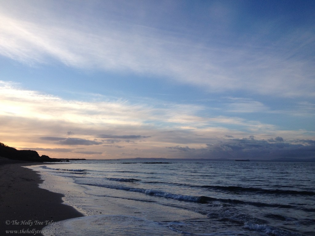 Beautiful sky with windswept cloud and blue tones, at the coast. Waves along the shore. Signed (c) TheHollyTreeTales.com