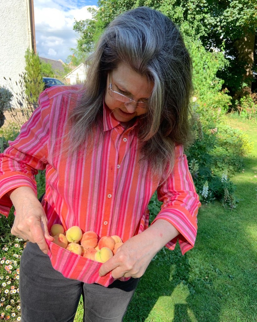Lady with peaches in an organic garden. (c) Holly M Maxwell Boydell www.TheHollyTreeTales.com